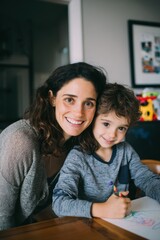 Obraz premium Mothers Day, Valentines Day, love holiday theme. A woman and a young boy sitting at a table, drawing with colored pencils. The table is in front of them.
