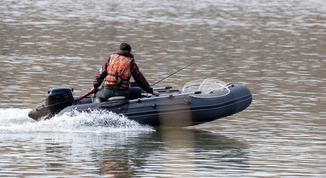 A fisherman in a rubber boat with a motor on the Irtysh River in Kazakhstan at the beginning of winter
