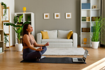 Pregnant woman meditating in lotus position at home
