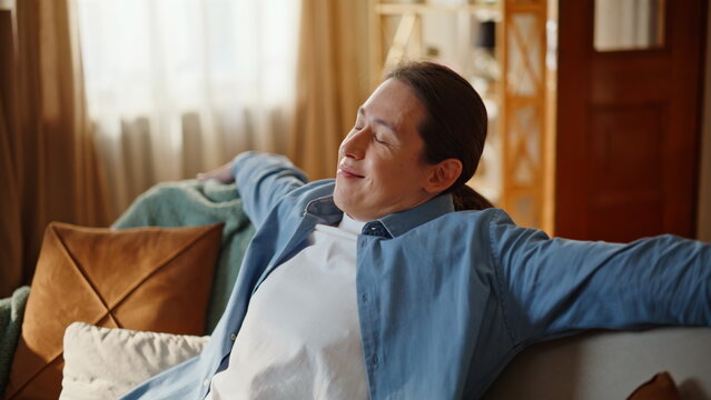 Closeup guy falling couch feeling happy at home. Lazy man taking rest chilling