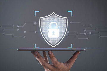 Cybersecurity shield with lock icon on digital tablet in human hand, representing data protection, network security, privacy, encryption, digital trust, information safety, and cyber defense concept.