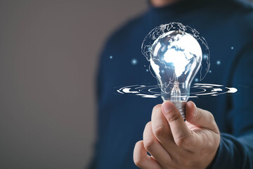Hand holding glowing light bulb with world map inside, symbol of global innovation, digital knowledge, technology advancement and creative ideas connecting business, communication worldwide solutions.