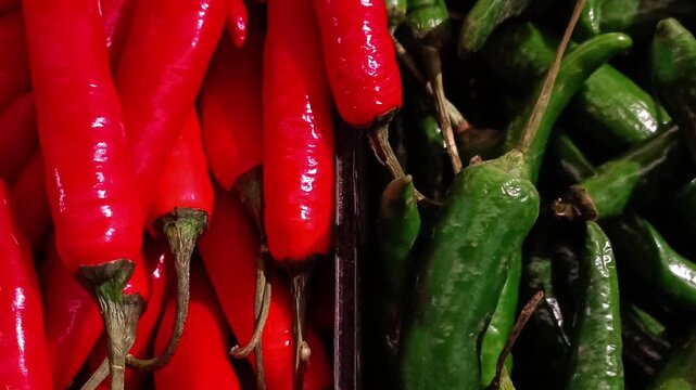 Zoom out footage of fresh red and green chili peppers arranged side by side, revealing strong color contrast and natural texture. 