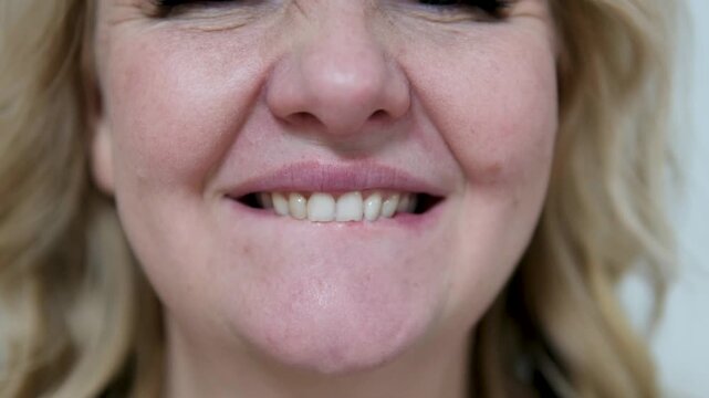Woman bites her lips. Nervous tic. Obsessive-compulsive disorders. Patient of a psychiatric clinic biting lips, scratch face, biting nails, eye twitching. Close up, macro. 