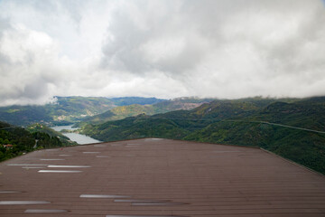 Miradouro moderno com vista para vale montanhoso e rio.