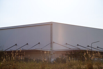 Warehouse Factory Industry Building with Geometric Metal Corrugated Steel Wall and Rooftop against Blue Sky Background, Modern Industrial Exterior Architecture Backdrop Structure in Minimal Style