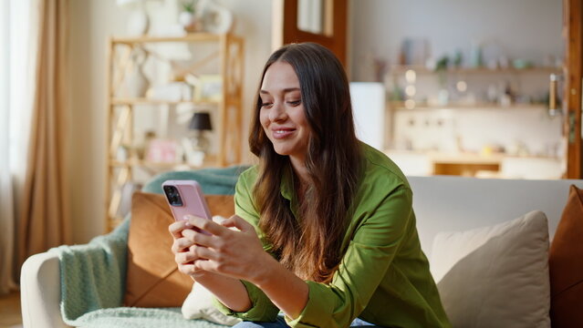 Satisfied woman shopping online using mobile phone app sitting sofa closeup