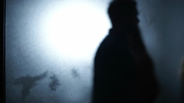 Silhouettes of a Man and Woman Separated by Conflict, Seen Through Frosted Glass: Dramatic Abstract Scene Representing Relationship Crisis, Isolation, Fear, or Domestic Issues.