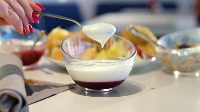 A person uses a spoon to mix and scoop cendol dessert in a ceramic bowl, under soft indoor lighting, with a close-up, steady camera angle