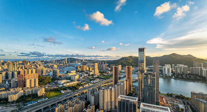 Beautiful panoramic view of Macau and Zhuhai cityscape with skyscrapers and mountains during sunset.