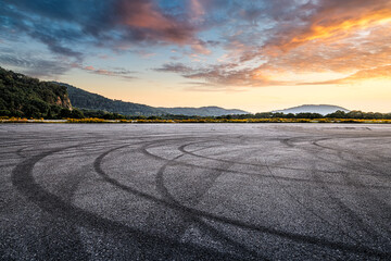 Dramatic asphalt ground with tire skid mark in a mountain landscape during sunset. © zhao dongfang