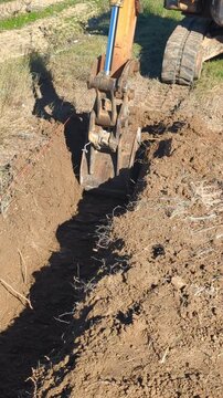 Excavator digging trench in a field