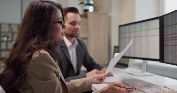 Colleagues reviewing data report on computer screens. Analysts discuss finance in office, comparing sheets on screens and a print align budgets and forecast. Business team concept in office.