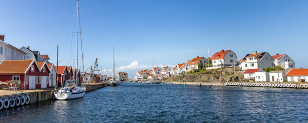Astol island near Tjorn in Sweden with red and white cottages, boats and blue water