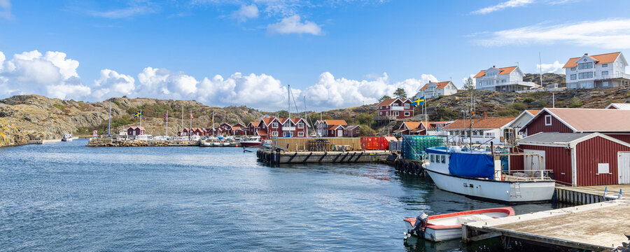 Harbor scene island Stora Dyron in Sweden, with red houses, flags, and moored boats by the dock