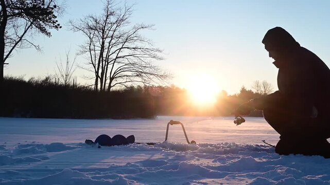 Rising sun, ice fishermen in silhouette fishing, winter activity