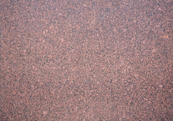 Close-up of a dark brown speckled composite material surface with a subtle highlight and varied granular texture.