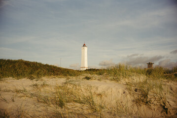 K&uuml;stenlandschaft in Bl&aring;vand mit Leuchtturm und Sonne