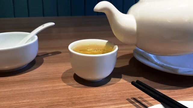 Chinese China Japanese Japan Drink Pour Serving Tea Ocha Green Gold Brown Yellow Clear Teapot Mug White Cup Glass Ceramic Hot Warm Steamy Smoky Closeup Close Macro Cafe Restaurant Wooden Table. HD