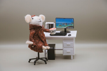 Cute felt mouse working at desk with computer and coffee, miniature office workspace concept, work from home, work remotly