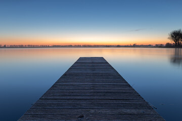 Fototapeta premium A pier on the lake in Dirkshorn during the blue hour. A moment of peace and serenity, to be fully present in the here and now.
