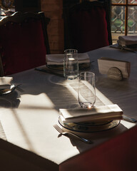 Sunlit dining table with elegant place settings and soft shadows