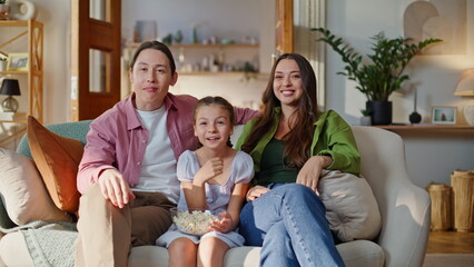 Domestic family eating popcorn at home sofa closeup. Couple child watching tv