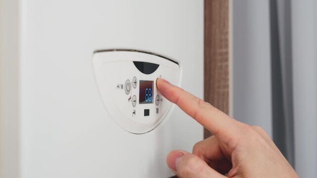 silhouette person turning on boiler heating appliance, human hand finger pressing button control dial of digital thermostat display to increase operating temperature heating system. utility bills 4k