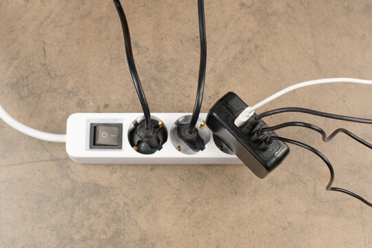 Extension power outlet socket overloaded with plugs, USB adapter with charge cables plugged into power strip