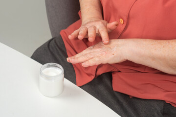 Wrinkles on mature hand with cream. Wrinkles treated with moisturizing hand cream. Aged hands natural skin texture with cream. Cream on aged hands.