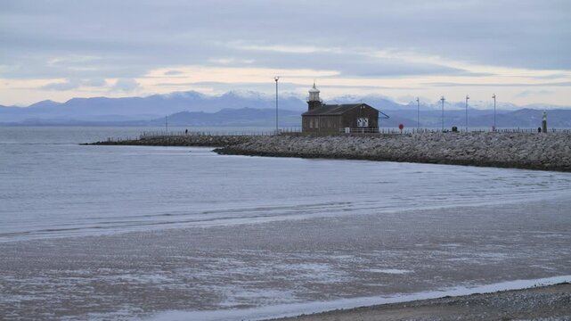 4K: The Stone Jetty in Morecambe on a cold, grey day. The Lake District fells are behind with snow on. Stock Video Clip Footage.