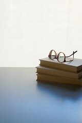 老眼鏡のイメージ　積み重ねらた本の上に置かれた老眼鏡