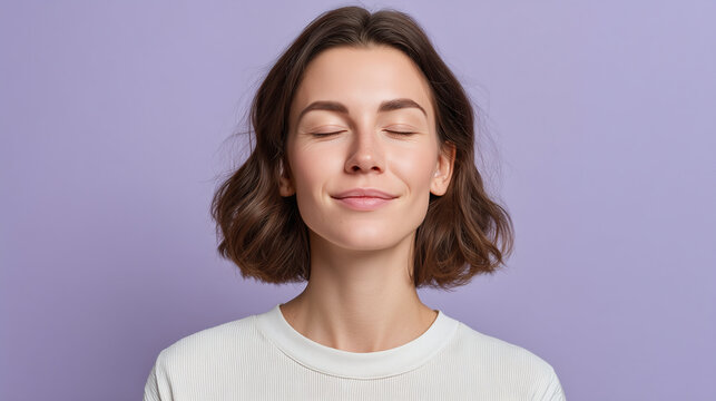 Young woman with shoulder length brown hair and eyes closed taking deep breath and feeling relaxed against purple background