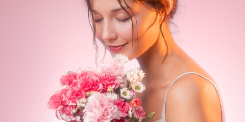 Smiling Woman Smelling Flowers In Soft Pink Light