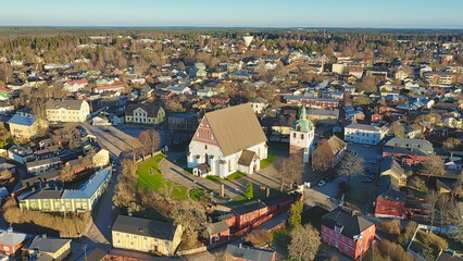 Obraz premium Porvoo, Finland - December 08, 2020: Aerial perspective of a picturesque town featuring a historic church surrounded by colorful buildings and lush greenery, showcasing urban beauty