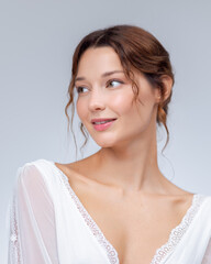 Elegant Woman In White Dress Smiling And Looking Aside On Light Background