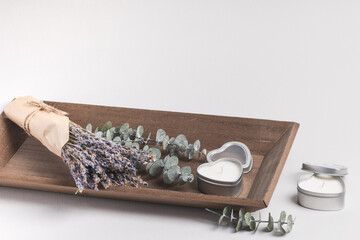 Wooden tray with a lavender bouquet, eucalyptus branches, and heart-shaped candles. A serene atmosphere, calm, and relaxation.