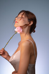 Sensual Beauty Portrait of Woman Holding Pink Flower Against Her Neck