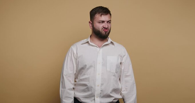 Man makes funny face in plain studio with yellow background during a lighthearted moment