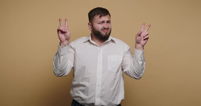 Man gestures with hands while making a face in front of a plain background