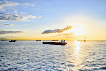 Cargo ships sailing at sunset, towards the port of Barcelona