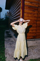Fototapeta premium woman dress yellow wooden drink outdoors evening portrait by log wall with authenticity inclusivity candid rural