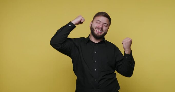 Man dances joyfully against a yellow background in a playful moment of self-expression and happiness