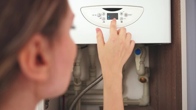 upset woman is trying to turn on broken boiler that showing error message on display heating appliance, person hand pressing button control dial screen. need help fix from technical service repairman