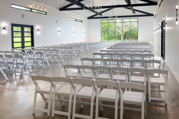 Bright event hall with white chairs arranged in rows prepared for event