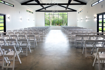 Minimal modern venue interior with rows of chairs large bright hall with white seats ready for formal event