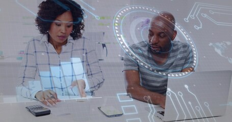 Reviewing papers, coworkers using laptop at desk, wearing plaid and striped shirts, calculator HUD