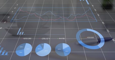 Displaying translucent blue multi-line chart, donut and pie charts overlaying desk, with cup, spoon