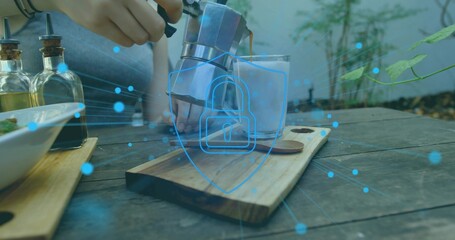 Pouring woman in short-sleeve top, bracelets pouring moka pot into glass on patio, shield overlay