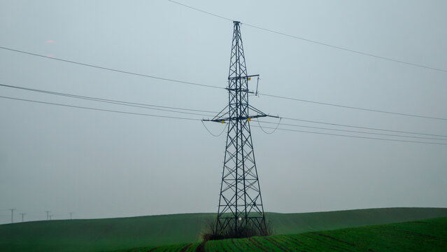 High-voltage transmission line in the middle of a field on a cloudy day